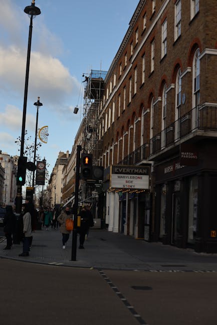 The image shows the exterior of a red brick building on a street corner in Marylebone, Westminster, with visible signage including 'Providence Court W1' and 'Balderton Street W1'. Two movers, dressed